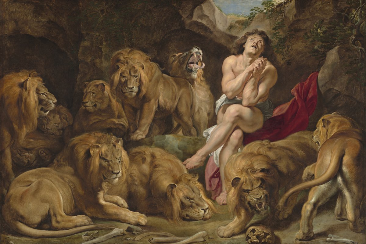 A baroque painting of a man sitting calmly among a pride of lions in a rocky den, praying with clasped hands.