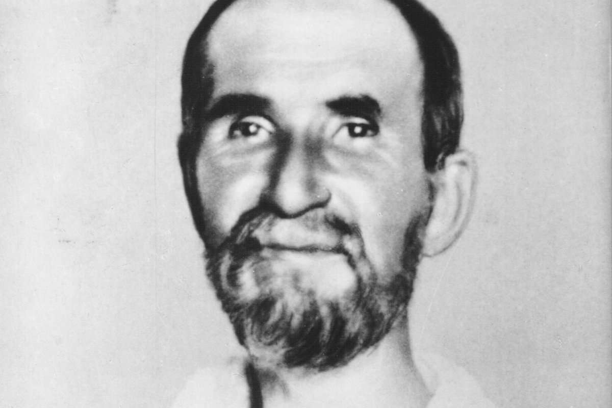 A black-and-white portrait photograph of Charles de Foucauld in later life, bearded and wearing the plain white habit of his desert hermitage.