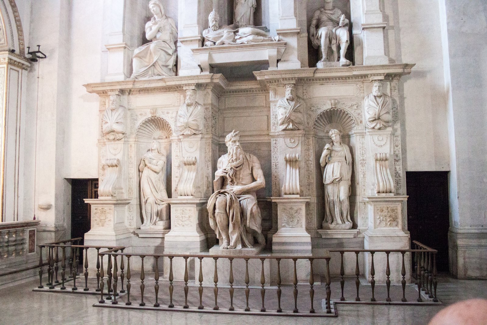 Michelangelo's marble statue of Moses seated, holding the tablets of the Law, with a long flowing beard and two small horn-like projections on his head