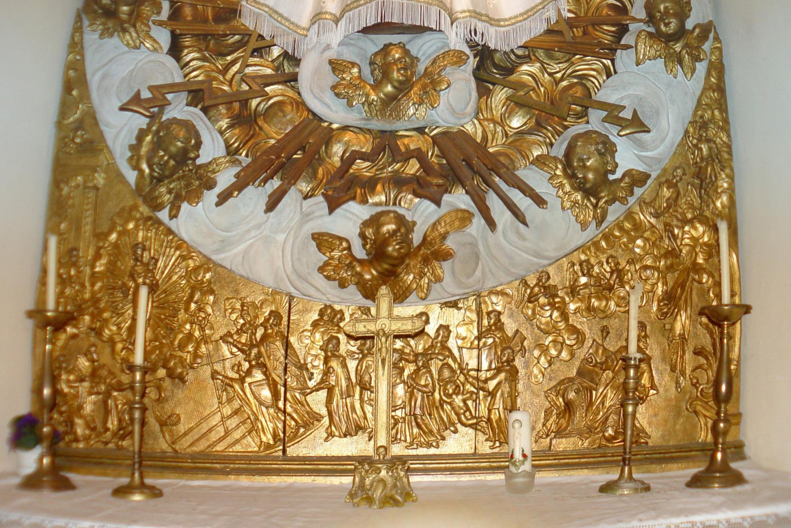 The dark-faced statue of Our Lady of Einsiedeln dressed in an ornate embroidered gown, set within a gilded Baroque niche surrounded by carved angels and golden rays