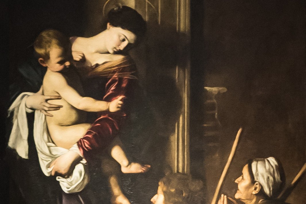 Caravaggio's Madonna di Loreto, showing Mary standing in a doorway holding the infant Jesus, as two barefoot pilgrims kneel before her.