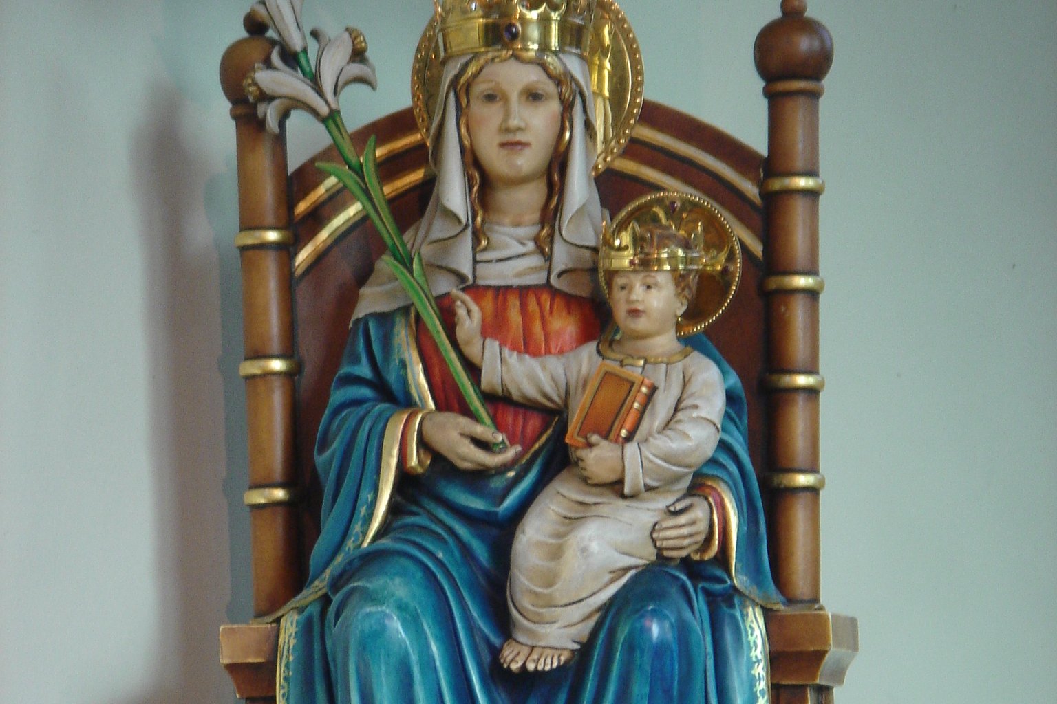 A carved and painted statue of Our Lady of Walsingham, showing the enthroned Virgin and Child holding a lily scepter, venerated at the shrine in Norfolk, England