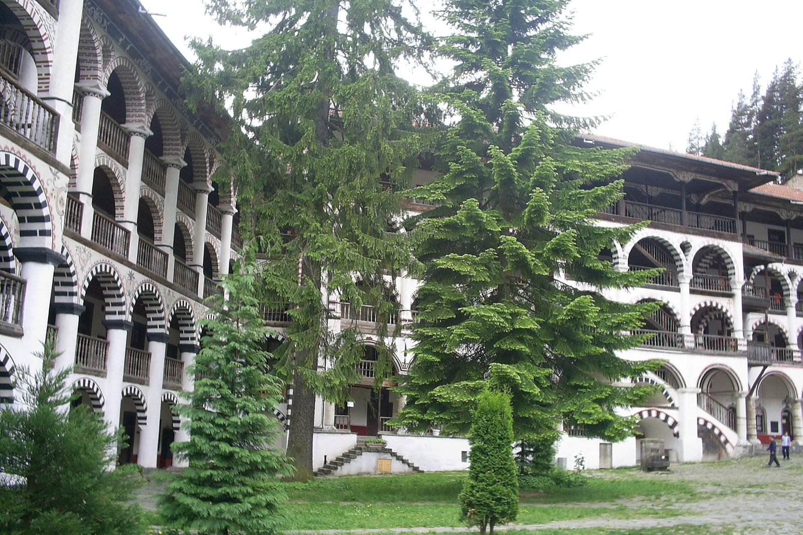 The striped arched courtyard and colorful frescoed walls of Rila Monastery in the Bulgarian mountains
