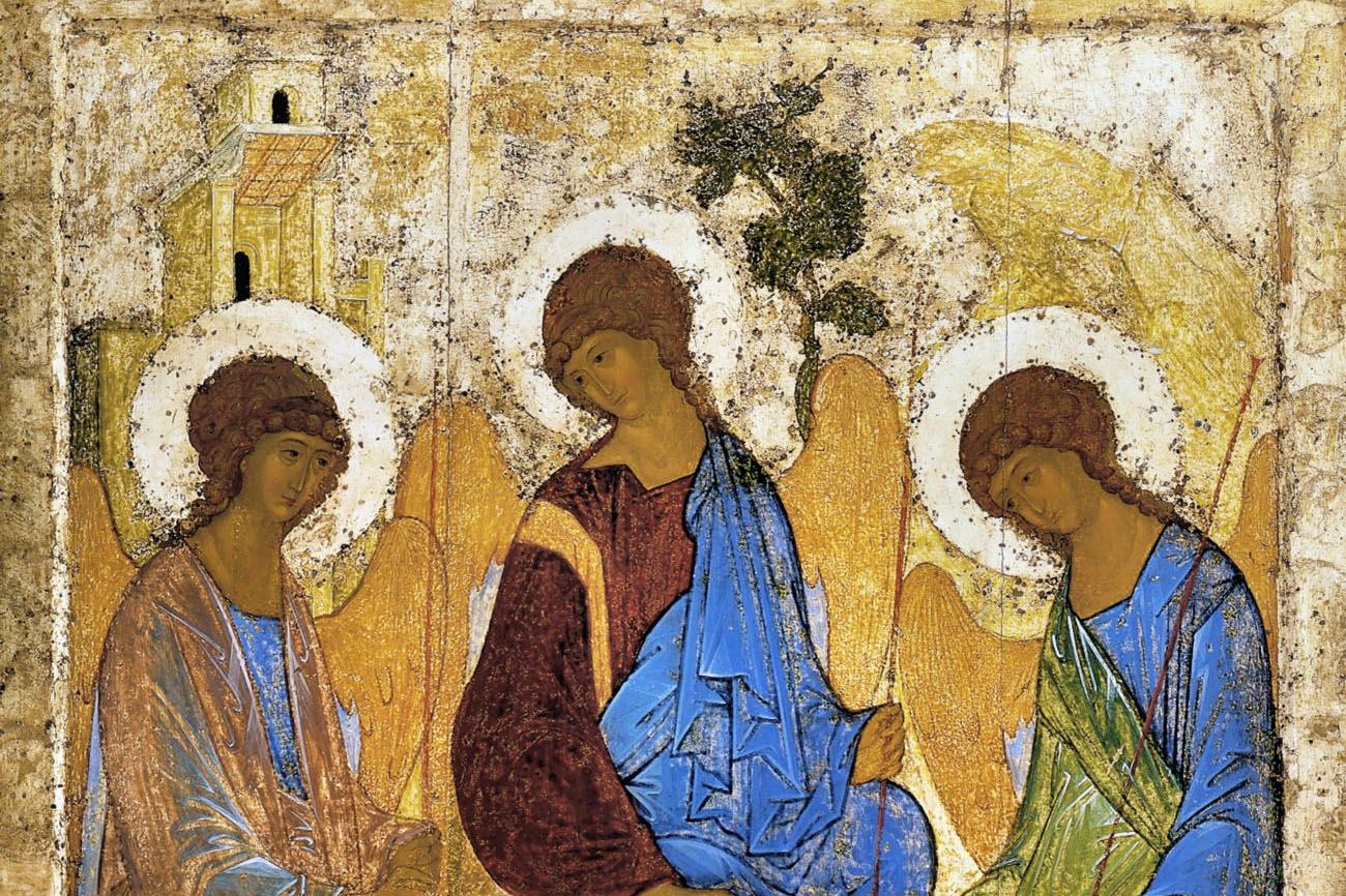 A medieval Russian icon of three winged angels seated around a table, each inclined gently toward the others, painted in soft golds, blues, and reds.