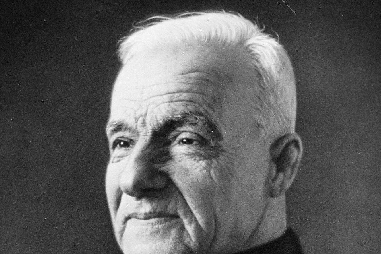 A black-and-white photograph of Brother André Bessette in his simple black religious habit.