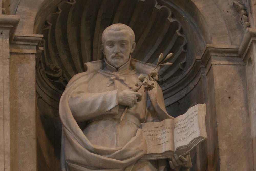 Marble statue of Saint Anthony Mary Zaccaria in clerical vestments holding an open rule book and a sprig of flowers