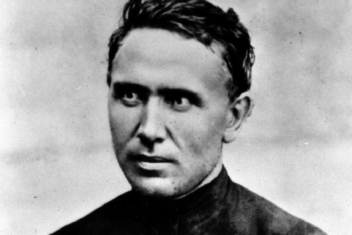 A portrait of a 19th-century Catholic missionary priest in a simple dark cassock, with a weathered, compassionate expression.