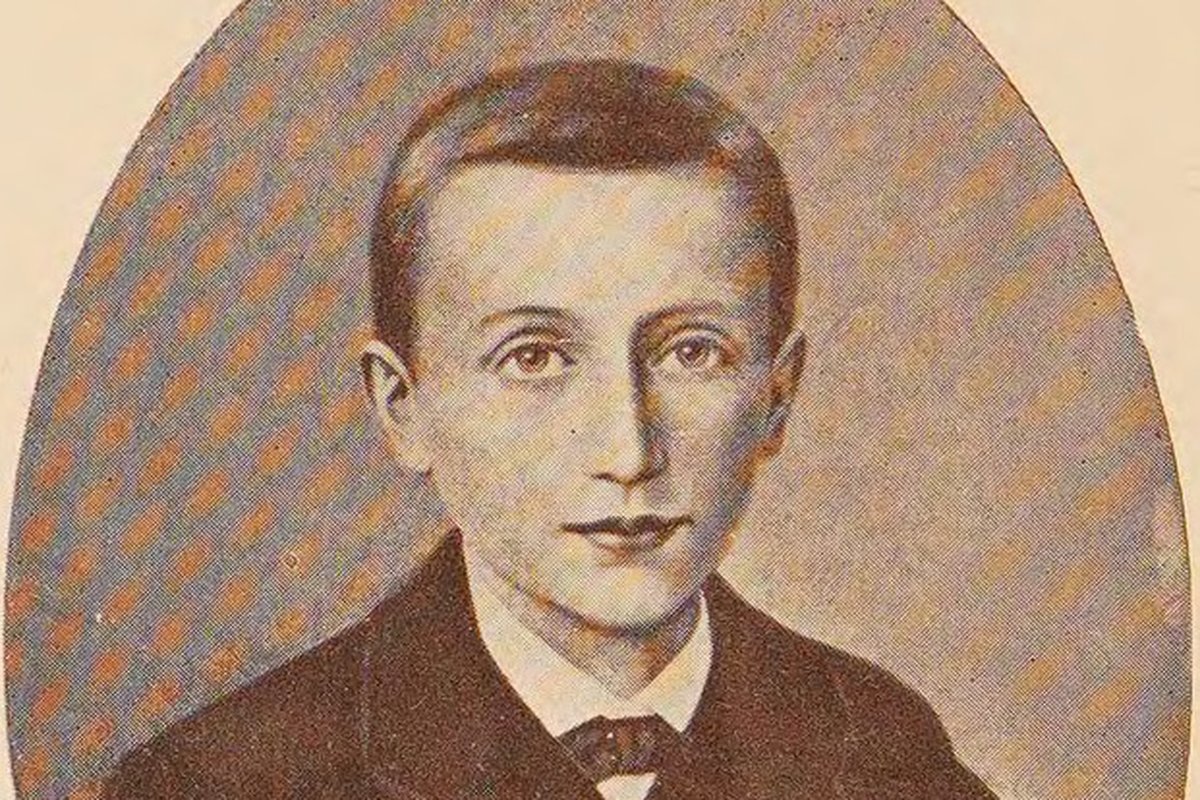A sepia-toned oval portrait of a young boy with short dark hair, dressed in a dark jacket with a white collar and bow, looking directly at the viewer.