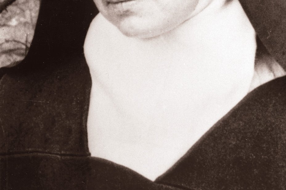 Ein Schwarz-Weiß-Foto einer jungen französischen Karmelitin in dunklem Habit und weißem Schleier, die ruhig in die Kamera blickt.