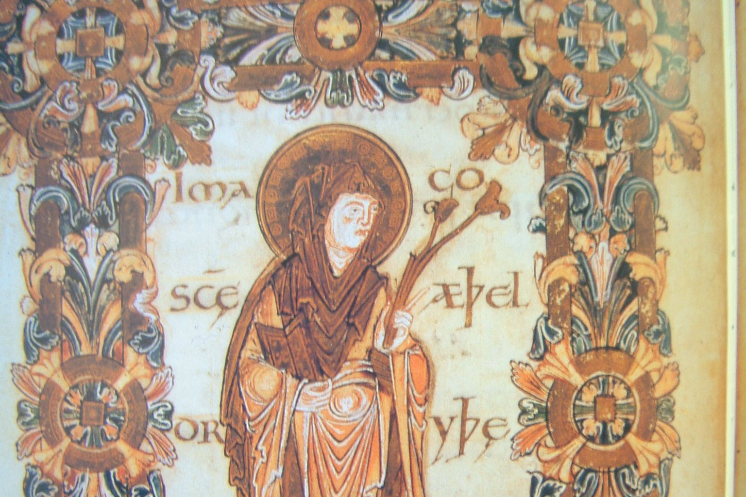 Peinture stylisée d'un manuscrit du Xe siècle représentant une femme couronnée en habits royaux, tenant un livre, debout de face sur un fond décoré.
