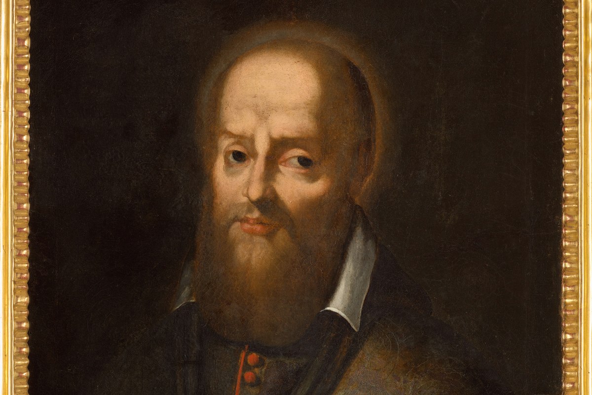 A portrait of a bald, bearded bishop in dark robes with a white collar, gazing forward against a dark background.