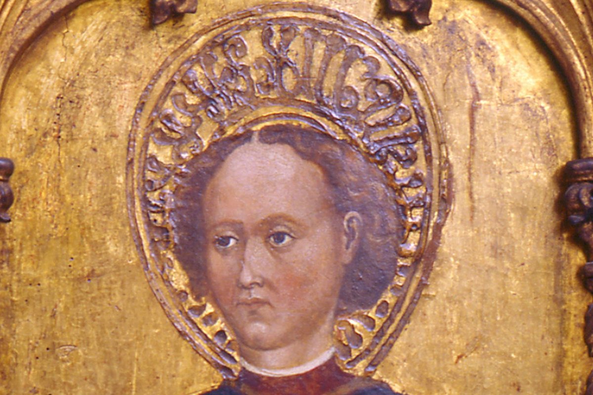 A Renaissance gilded panel painting of a young haloed saint against a gold background, framed by carved Gothic arches, from an altarpiece depicting Saint Genesius.