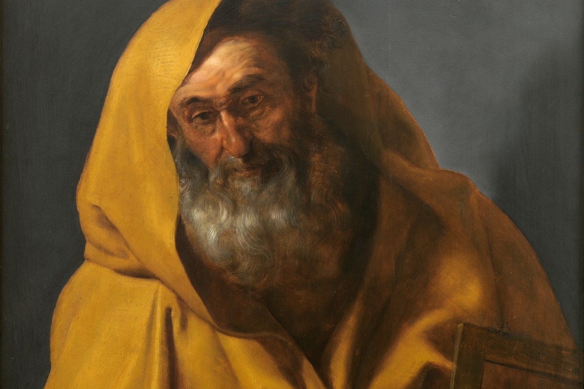 A close-up portrait of a bearded man in profile wearing a red cloak over a green garment, holding an object in one hand.
