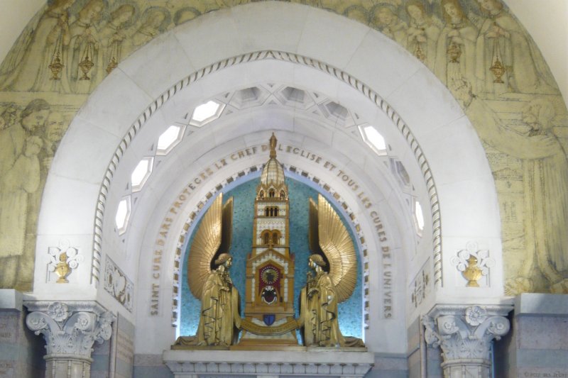 The gilded reliquary tower holding the heart of Saint John Vianney, flanked by two kneeling gold angel statues, in the Chapelle du Cœur at Ars-sur-Formans, France