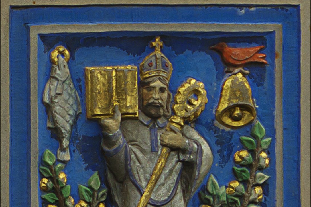 A carved and painted relief of a mitred bishop-saint holding a book and crozier, surrounded by a fish, a bell, a bird, and a tree — the traditional emblems of Saint Kentigern.