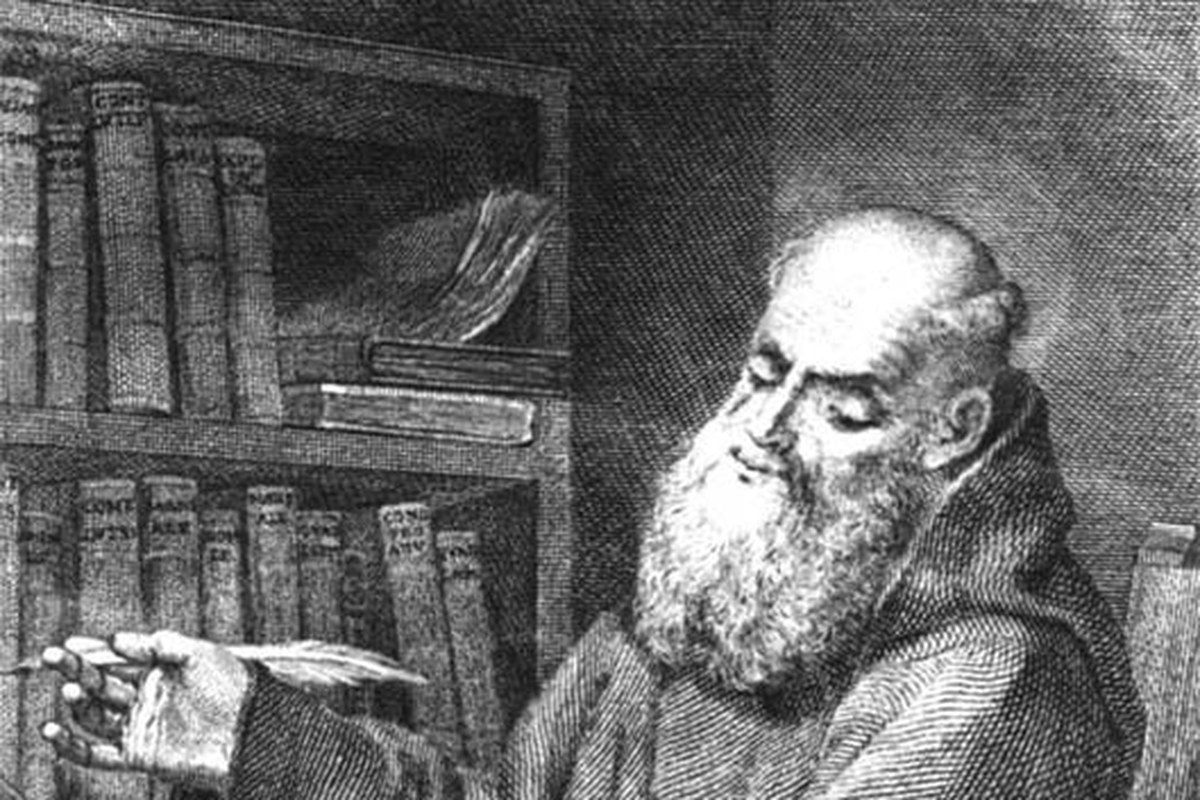 Ein Kupferstich aus dem 18. Jahrhundert, der einen alten bärtigen Ordensbruder in einer Kutte mit Kapuze zeigt, an einem Schreibpult sitzend, eine Feder in der Hand, neben einem Bücherregal.