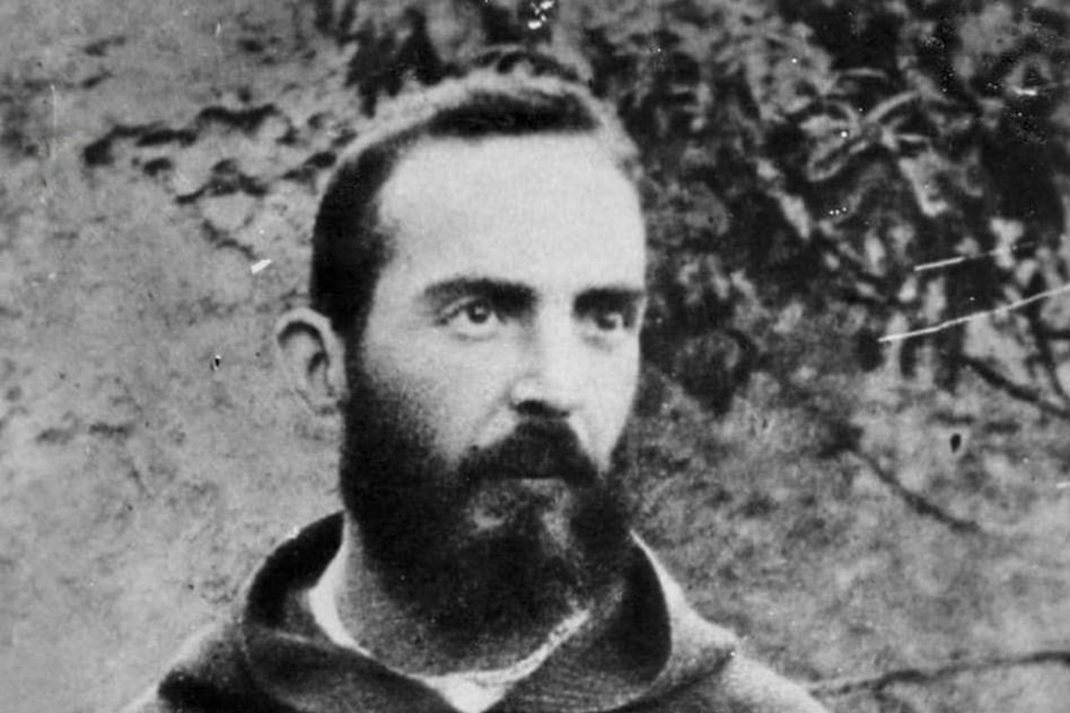 Schwarz-Weiß-Fotografie eines jungen, bärtigen Padre Pio in seiner Kapuzinerkutte, verschränkte Arme, aufgenommen 1919.