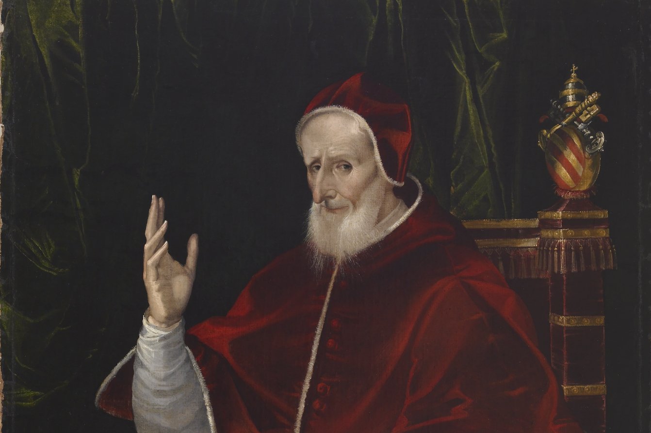 Renaissance portrait of Pope Pius V in red papal vestments and cap, hand raised in blessing, with the papal tiara and keys beside him