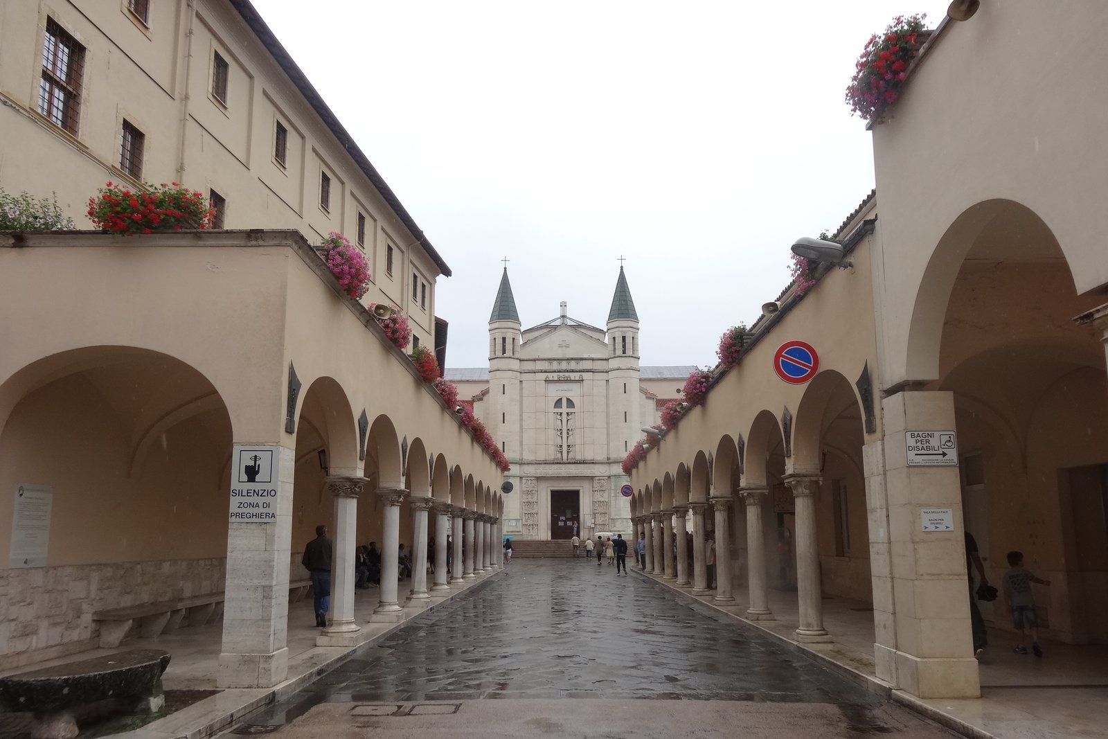 The colonnaded approach to the Basilica of Santa Rita in Cascia, Italy, with the twin-towered facade visible at the end of the arcade