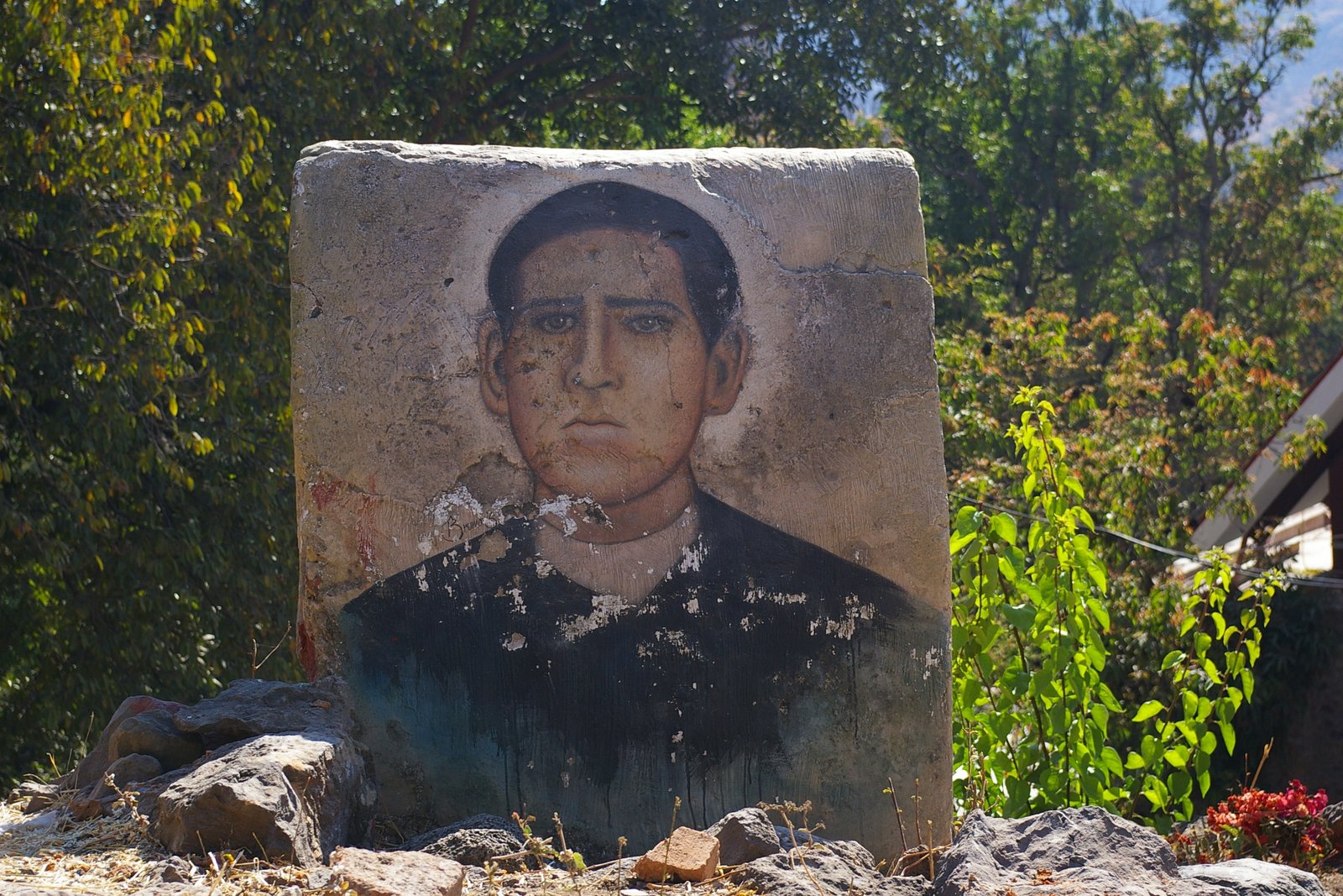 Un portrait photographique en noir et blanc d'un jeune prêtre catholique mexicain en soutane, regardant calmement l'objectif.