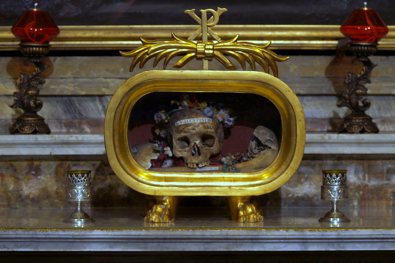 A skull crowned with dried flowers, venerated as a relic of Saint Valentine, displayed in a glass case at the Basilica of Santa Maria in Cosmedin in Rome