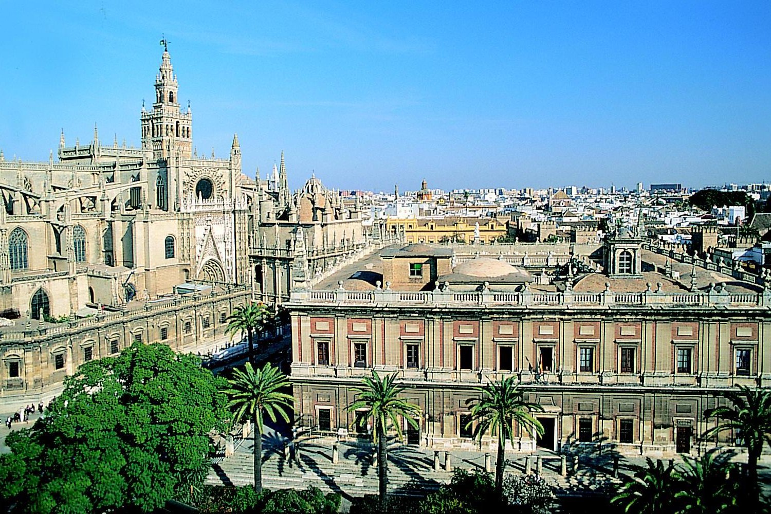 Vista exterior de la catedral de Sevilla, España, con la torre de la Giralda elevándose junto a ella, vista desde el Patio de los Naranjos.