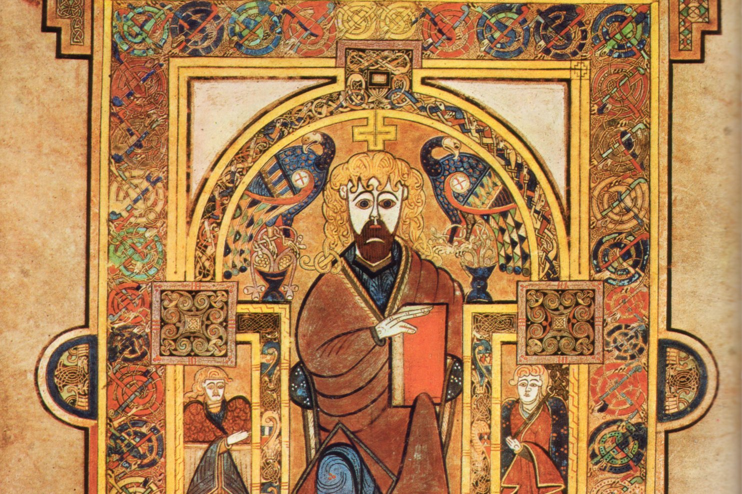 Illuminated page from the Book of Kells showing Christ enthroned, surrounded by intricate interlace patterns, spirals, and richly decorated borders in vivid color.