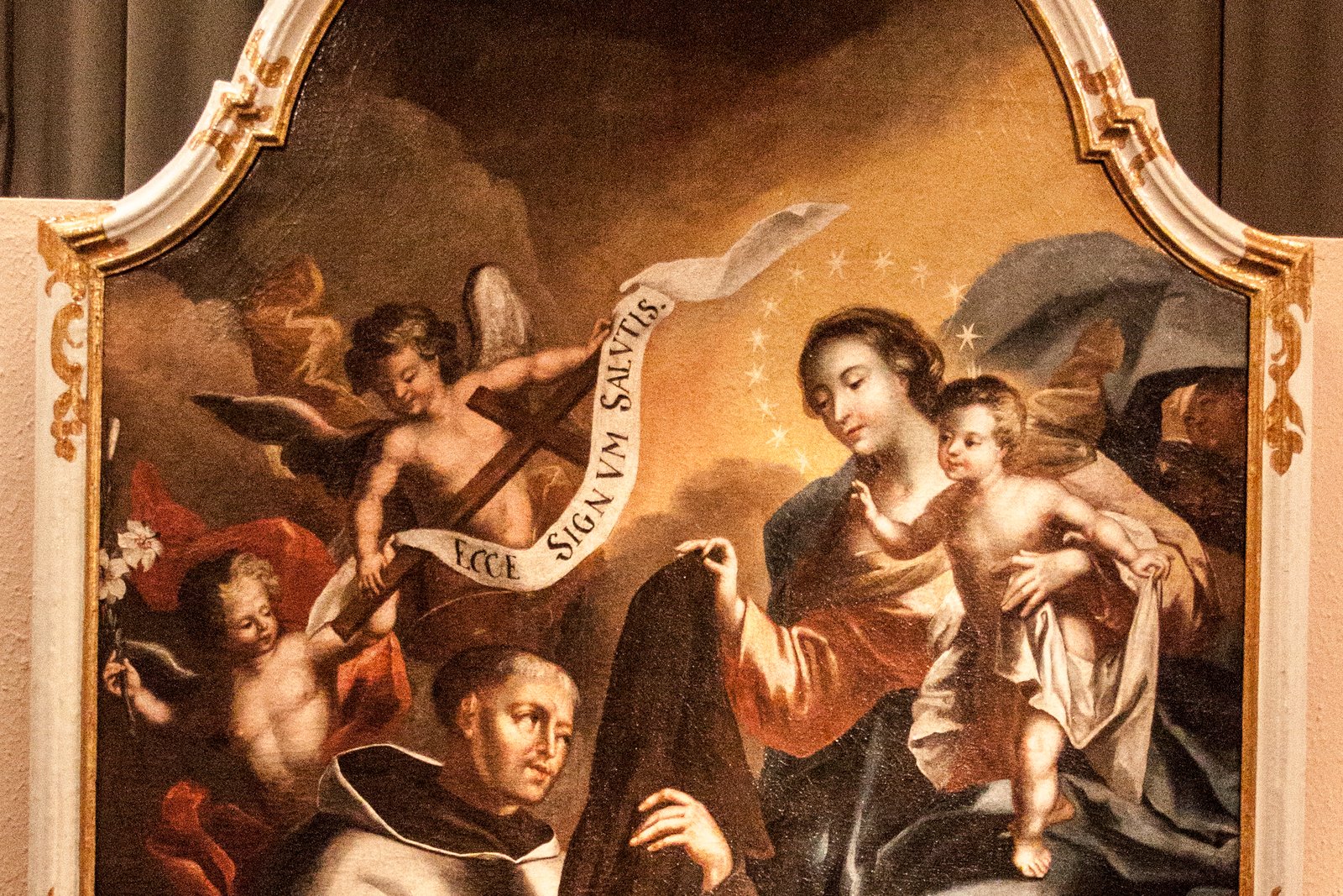 An 18th-century painting of the Madonna holding the Christ Child while extending a brown scapular garment toward the viewer.