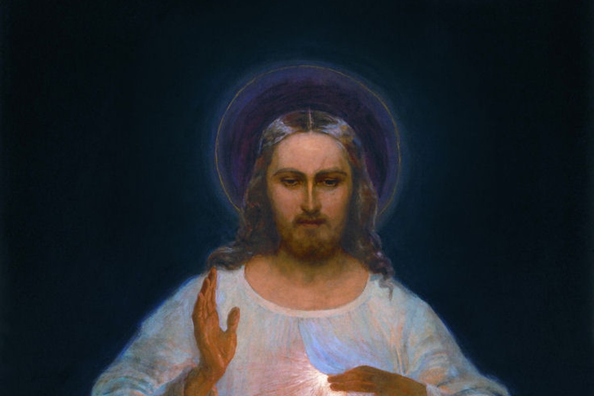A devotional depiction of Jesus in a white garment with red and pale rays streaming from his heart, one hand raised in blessing.