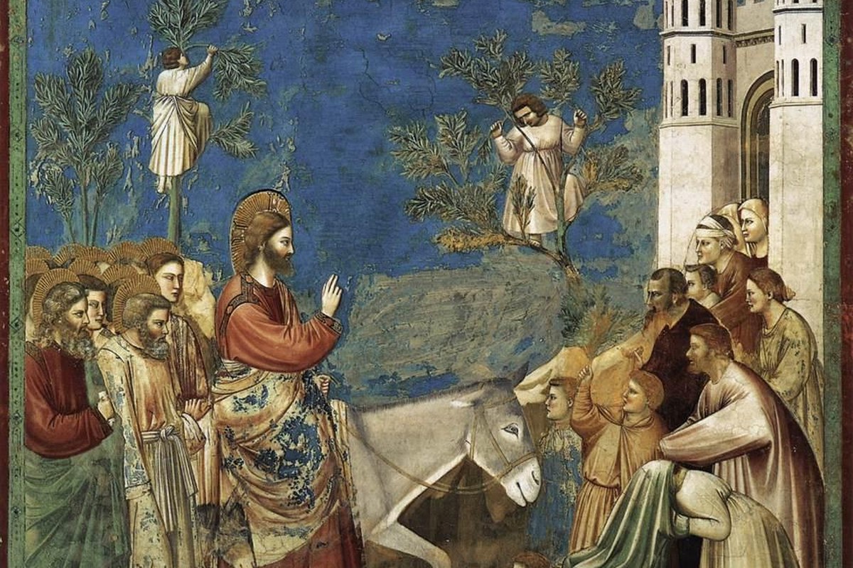 A medieval fresco of Jesus riding a donkey toward a walled city gate, greeted by a crowd waving palm branches.