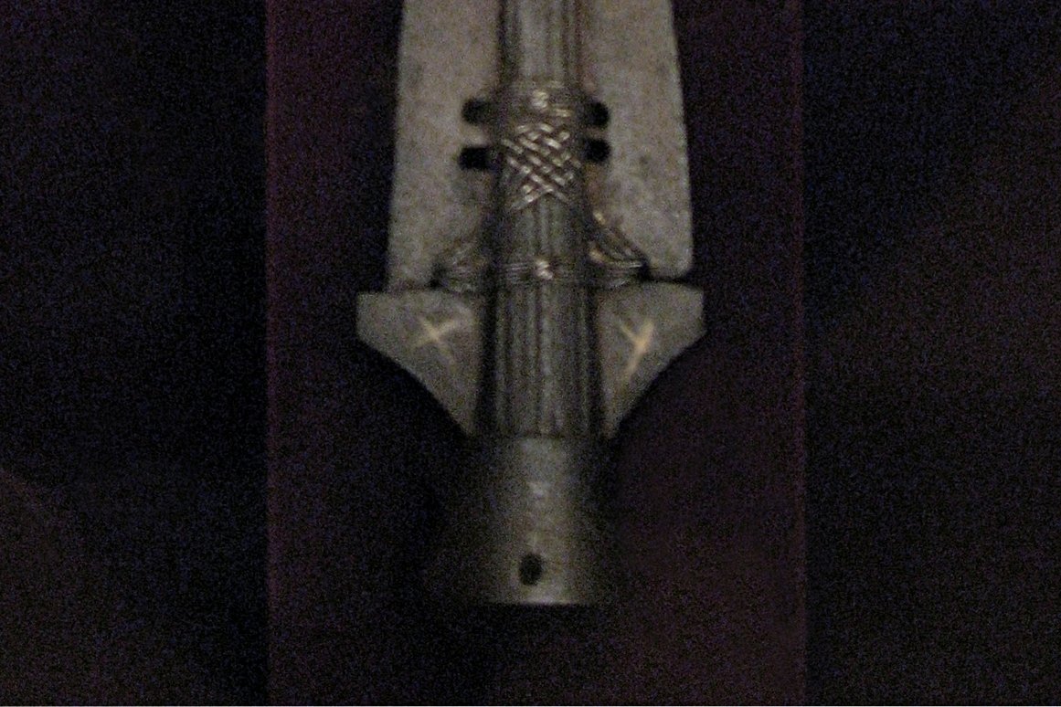 Close-up photograph of the Holy Lance of Vienna, showing its iron blade, silver binding wire, and the gold sleeve added to enclose a relic nail, displayed at the Hofburg Treasury
