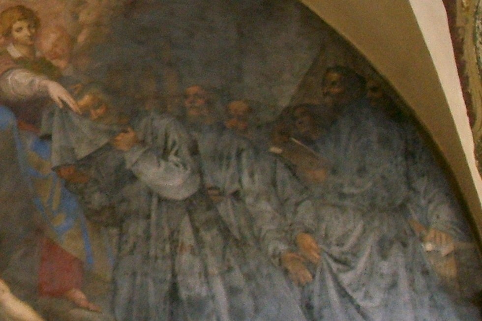A fresco detail of the seven founders of the Servite Order, dressed in gray monastic habits, gathered together as the Virgin Mary extends her mantle over them.