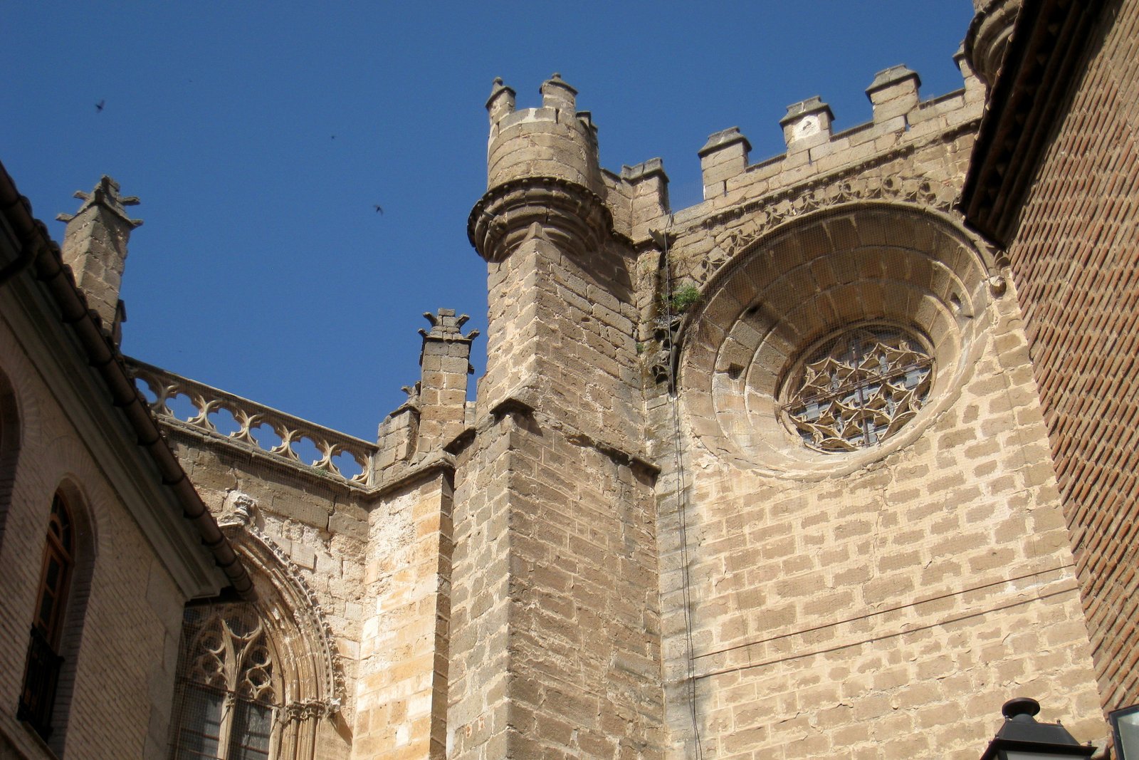 Vista exterior de la torre gótica y la fachada de la catedral de Toledo, España, contra un cielo azul.