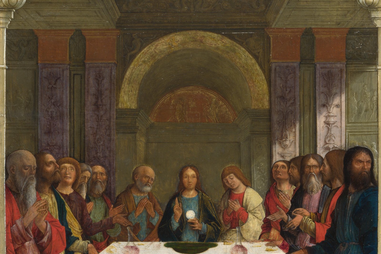 A Renaissance panel painting of Christ instituting the Eucharist at the Last Supper, breaking bread and offering the cup to his seated apostles.